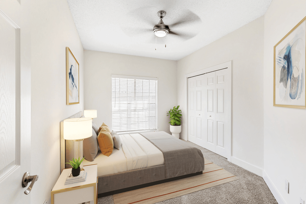 Virtually staged bedroom with carpet, bed, accent rug, nightstands with lamps, wall art, indoor plant, ceiling fan with light and large window with blinds